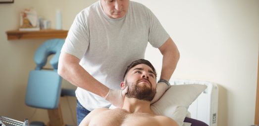 Physiotherapist examining neck of a patient in clinic Physiotherapist examining neck of a patient in clinic